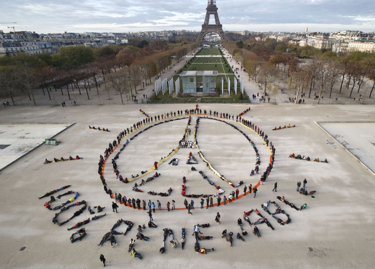 Environmentalist activists form a human chain representing the peace sign and the spelling out "100% renewable", on the side line of the COP21, United Nations Climate Change Conference near the Eiffel Tower in Paris, Sunday, Dec. 6, 2015. Negotiators adopted a draft climate agreement Saturday that was cluttered with brackets and competing options, leaving ministers with the job of untangling key sticking points in what is envisioned to become a lasting, universal pact to fight global warming. (AP PhotoMichel Euler)